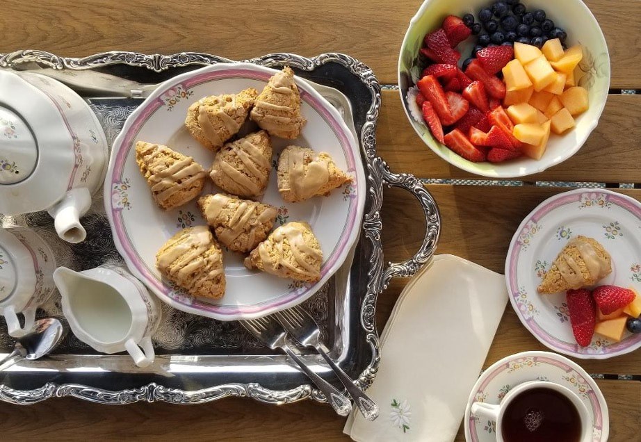 Scones served on a silver tray with fresh fruit and tea.