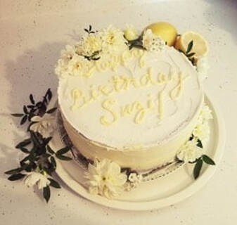 Elegant white cake decorated with flowers and 'Happy Birthday Suzy' inscription.