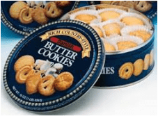 Open tin of rich butter cookies with assorted shapes.