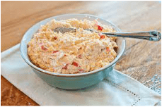 Bowl of creamy pimento cheese dip with a spoon.