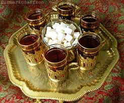 Traditional tea set with six glasses and sugar cubes on a brass tray.
