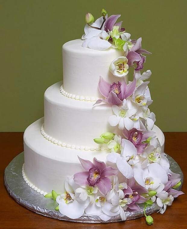 Elegant white tiered cake adorned with cascading orchid flowers.