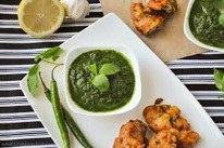 Green chutney served with fried snacks and lemon slices.
