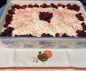 A dessert topped with whipped cream and berries in a glass dish.