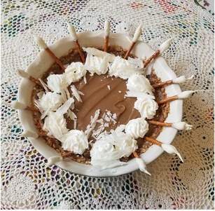 A bowl of chocolate mousse with whipped cream and chocolate sticks.