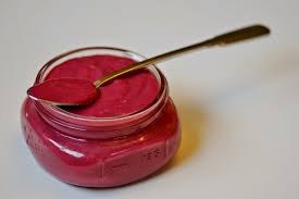 A small jar filled with vibrant pink beetroot puree and a spoon inside.