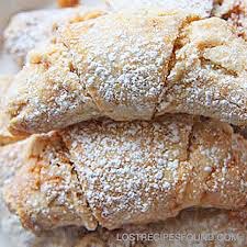 Two powdered sugar-dusted croissants on a white surface.