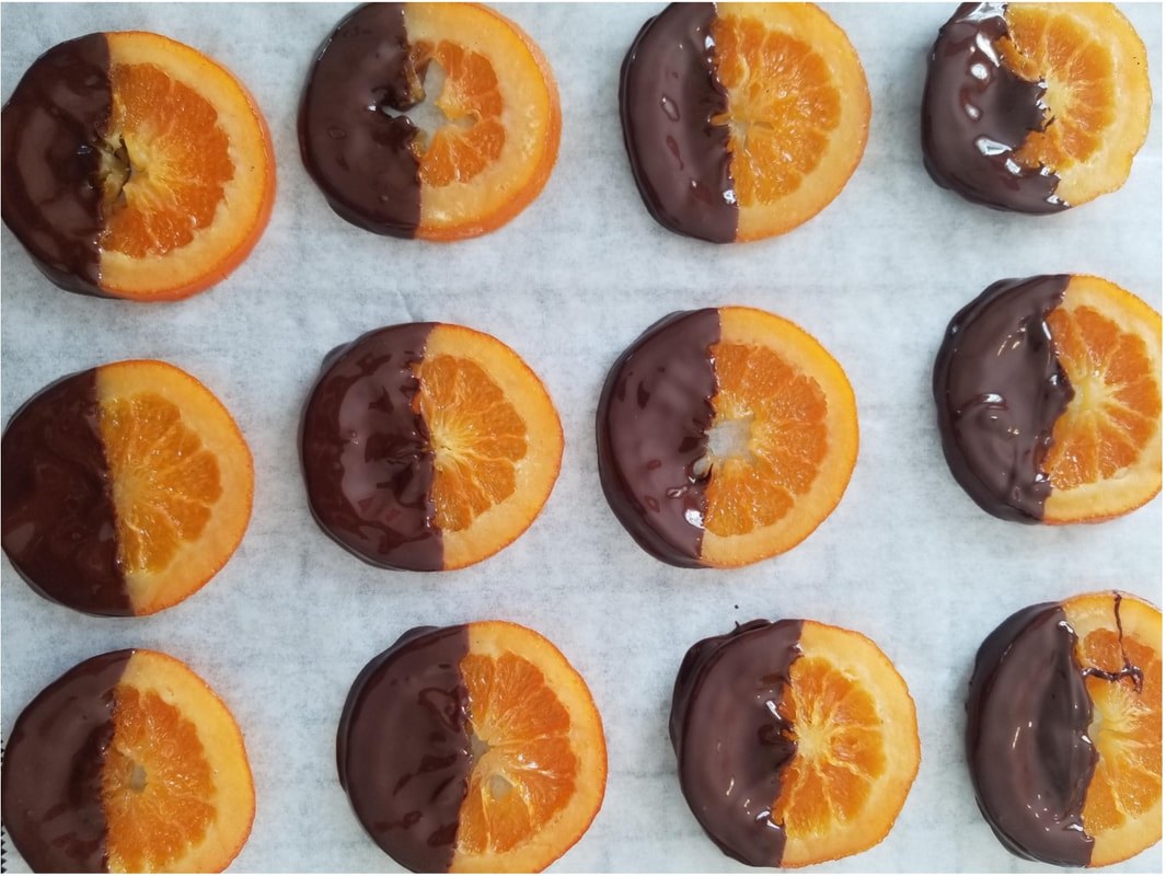 Chocolate-dipped orange slices arranged neatly on parchment paper.