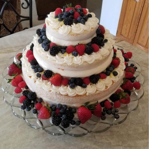 Three-tiered cake decorated with cream and fresh berries.