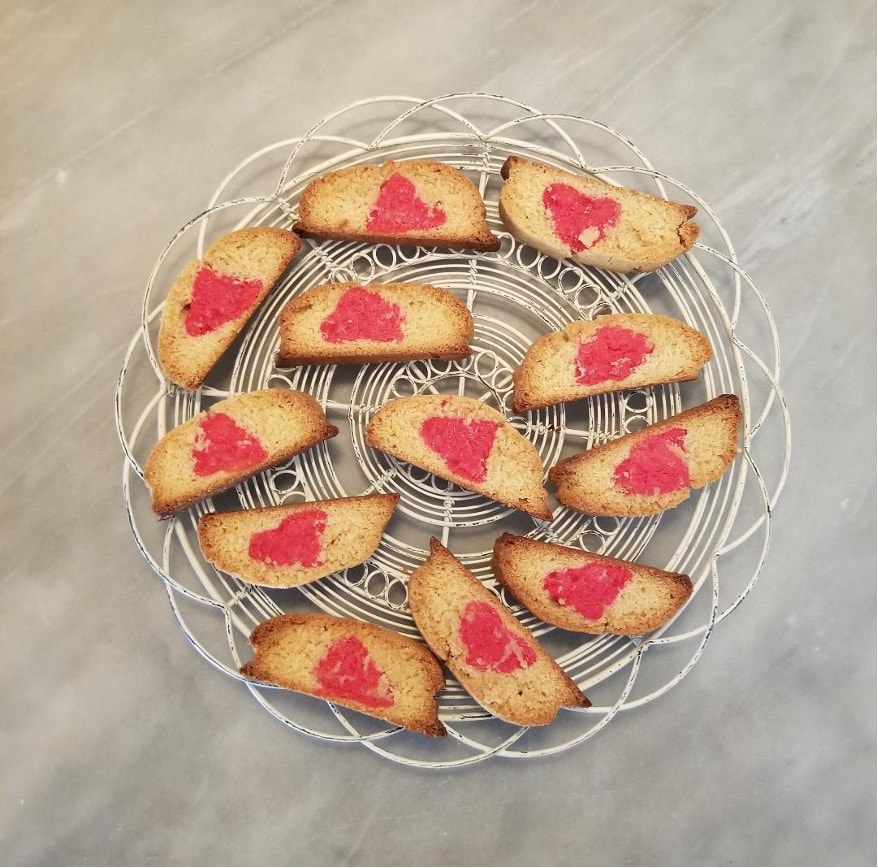 Heart-shaped jam cookies on a cooling rack.