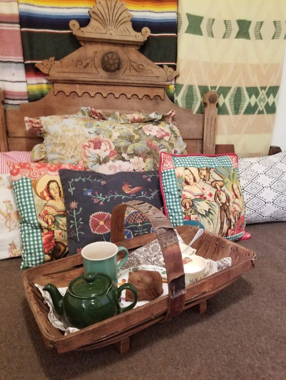 A decorative wooden boat with assorted vintage items and cushions in the background.