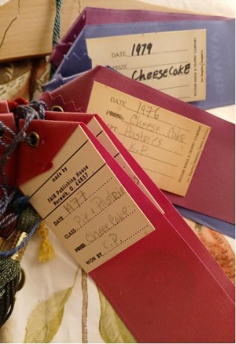 Two red notebooks with handwritten labels and a cheesecake menu.