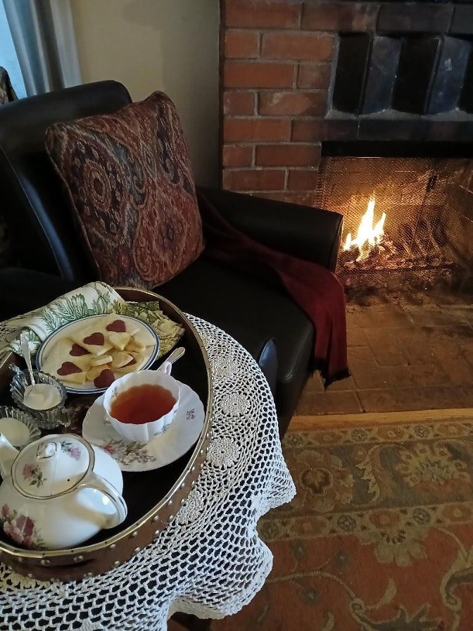 Cozy tea setup by the fireplace with scones and jam.