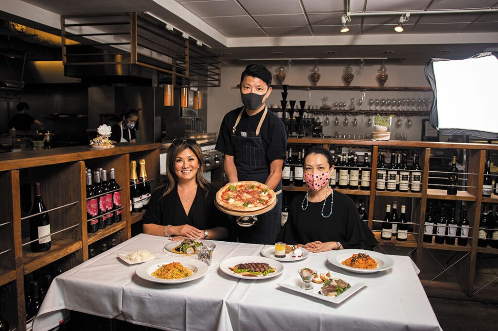 Three chefs presenting a variety of gourmet dishes in a restaurant.