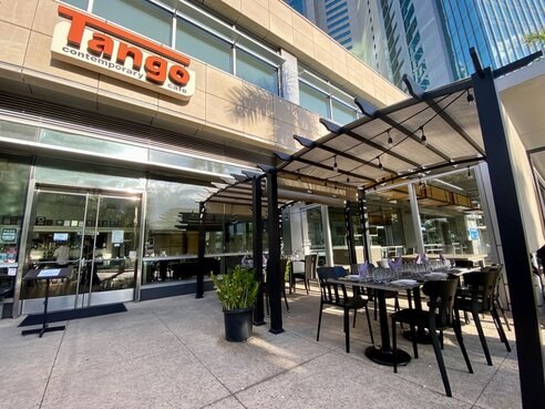Outdoor seating area of a modern restaurant in a city setting.