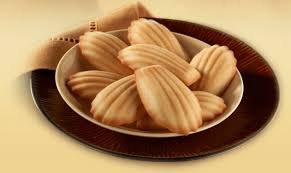 Plate of madeleine cookies on a brown dish.