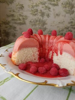 A raspberry dessert with white and pink layers topped with fresh raspberries.