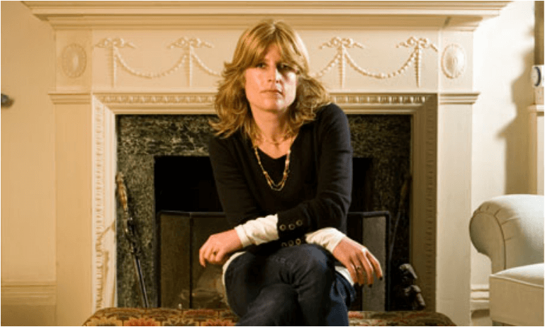Woman sitting in front of a fireplace with a calm expression.