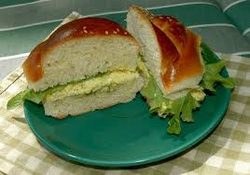 Two sandwich halves with egg salad on a green plate.