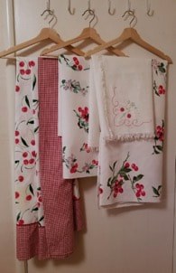 Set of floral and checkered patterned kitchen towels hanging on hooks.