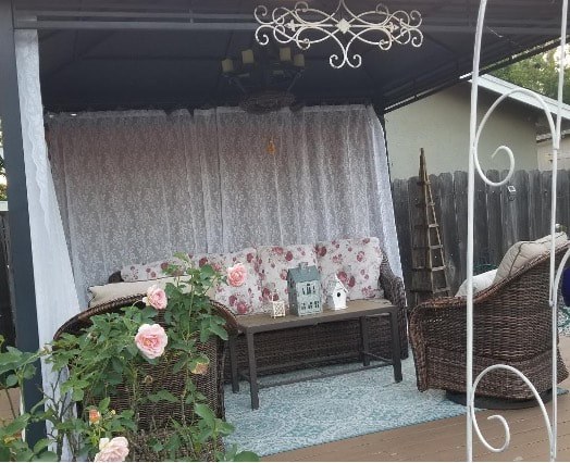 Cozy outdoor seating area with floral cushions and greenery.