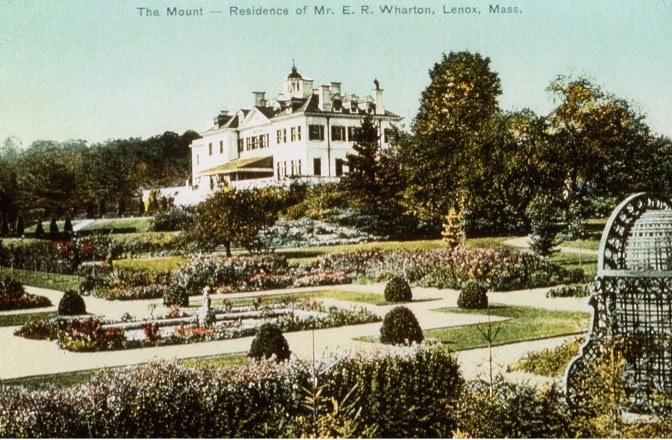 Historic mansion with ornate gardens under a blue sky.