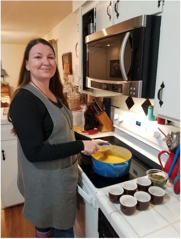 Woman cooking in a kitchen, smiling at the camera.