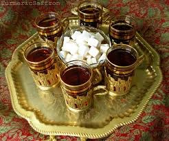 Traditional Moroccan tea glasses filled with tea and sugar cubes on an ornate tray.