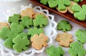 Green and beige shamrock-shaped cookies on a white doily.