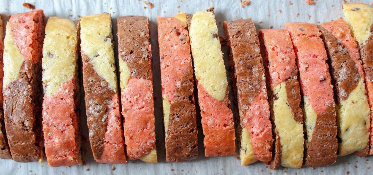 Sliced layered bread with colorful swirls of yellow, pink, and brown.