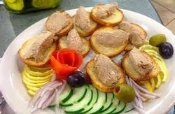 Slices of bread topped with a meat spread, garnished with fresh vegetables.