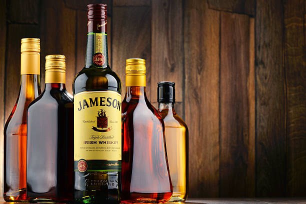 Three bottles of alcoholic beverages on a wooden surface with rustic background.
