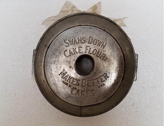 Vintage metal cake flour tin with engraved text.