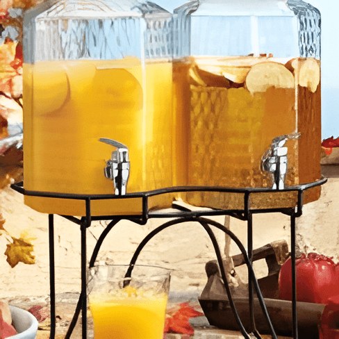 Two beverage dispensers filled with orange juice on a black metal stand.