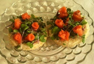 Two crackers topped with avocado and small carved carrot roses.