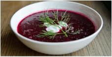 A bowl of beet soup garnished with dill and sour cream.