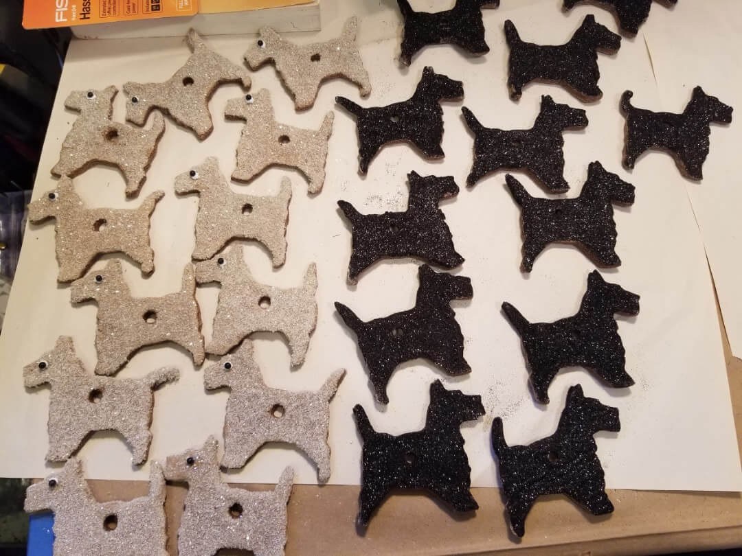 Rows of felt dog-shaped ornaments in beige and black colors.