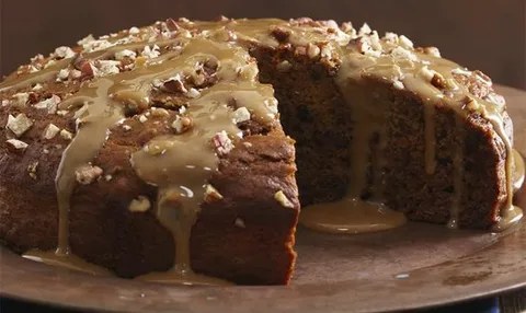 Close-up of a moist cake with glaze and nuts.