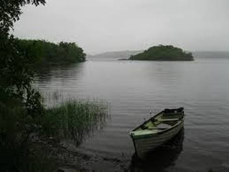 A small boat on a calm lake with islands and overcast sky.