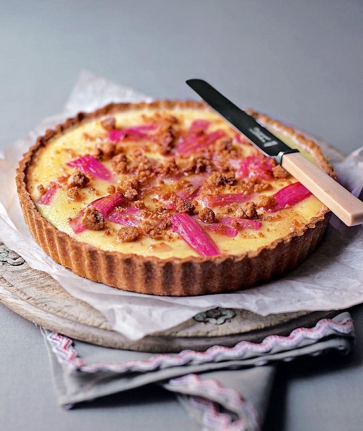 A creamy tart topped with pink petals and crumbled nuts.