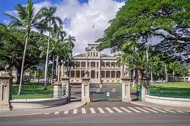 Historic government building flanked by palm trees under a blue sky.