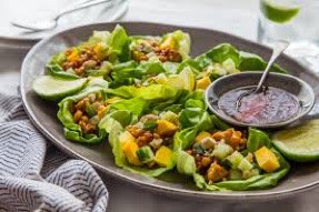 Lettuce wraps filled with diced chicken, corn, and sauce on a plate.