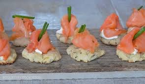 Smoked salmon canapés with cream cheese and chives on crispy crackers.