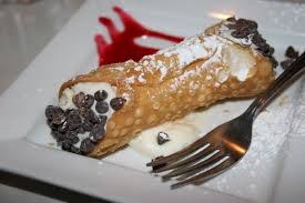 A cannoli dessert garnished with chocolate chips and powdered sugar.