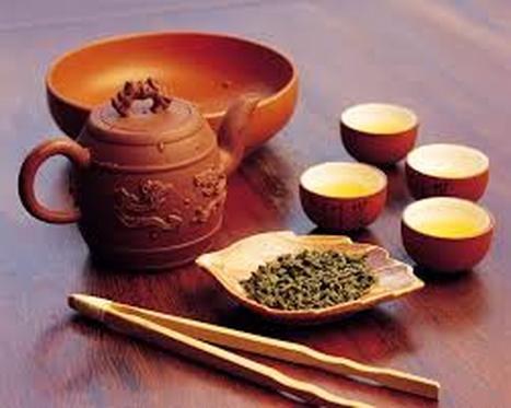 Traditional tea set with teapot, cups, and loose tea leaves.