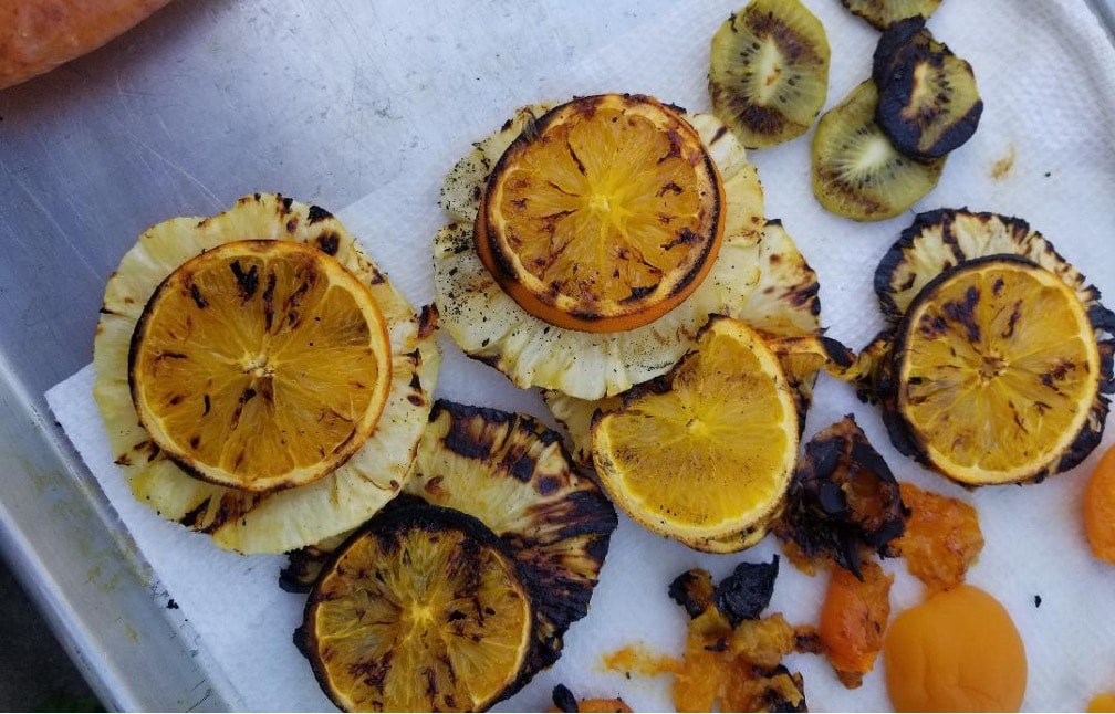 Grilled citrus slices with char marks on parchment paper.