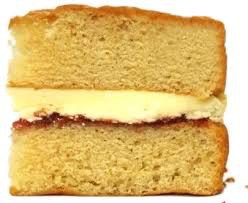 A close-up of a sponge cake with cream and jam filling.
