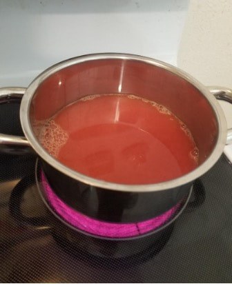 Pot of tomato sauce simmering on a stovetop burner.
