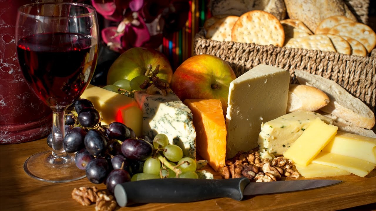 A rustic cheese platter with grapes, nuts, and bread.
