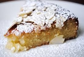 Close-up of a slice of almond cake dusted with powdered sugar.